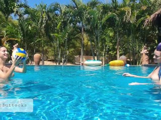 Bare teenagers play with a ball within the pool